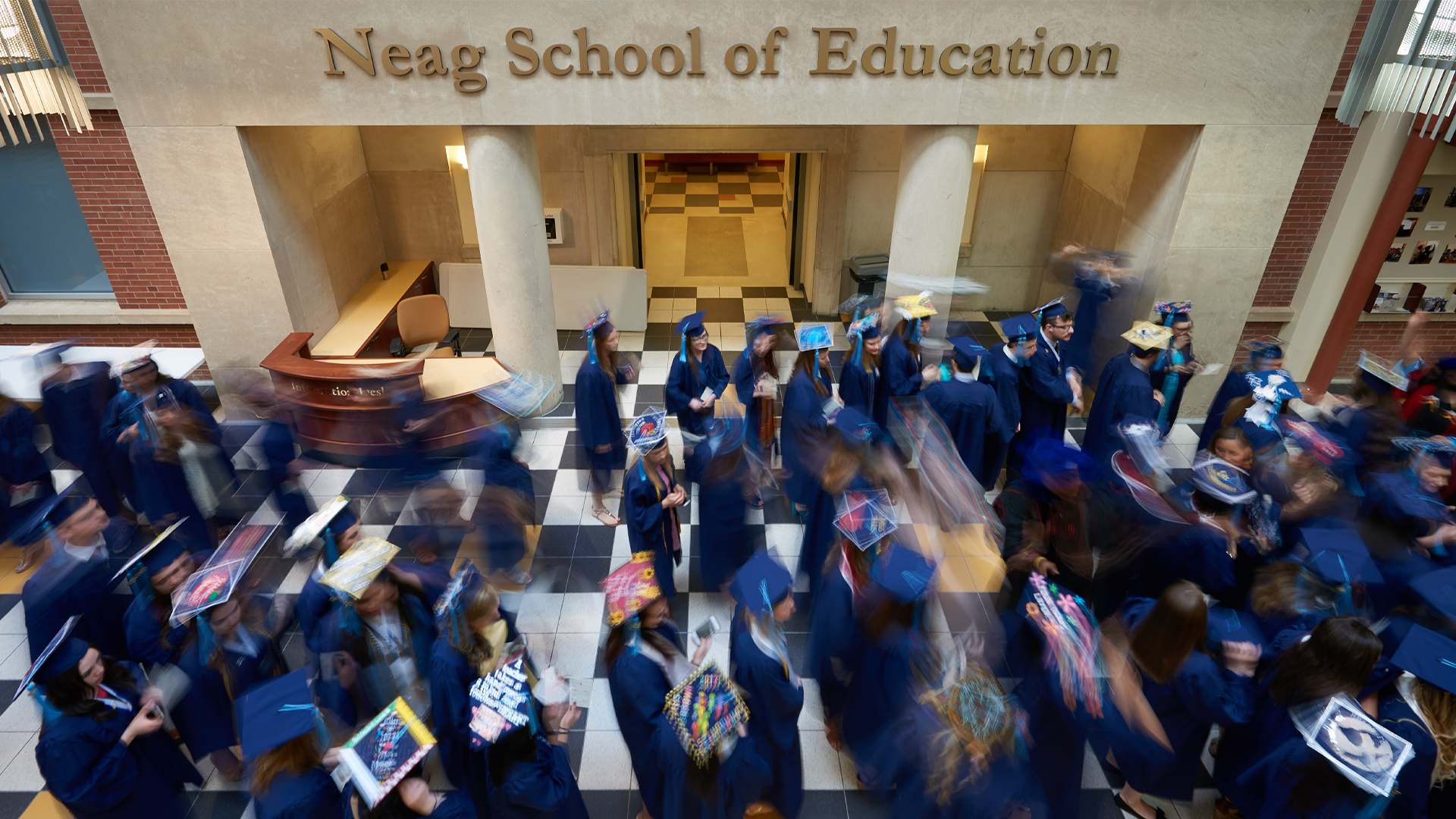 Neag School graduates blurred as they gather in the Gentry Building atrium before Commencement.